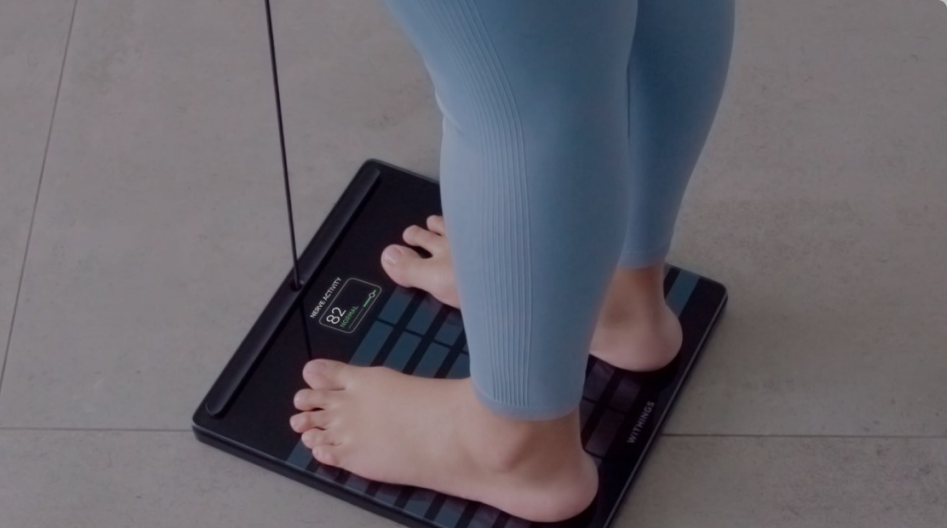 Close-up of a person’s feet on a Withings Body Smart scale in a home setting.