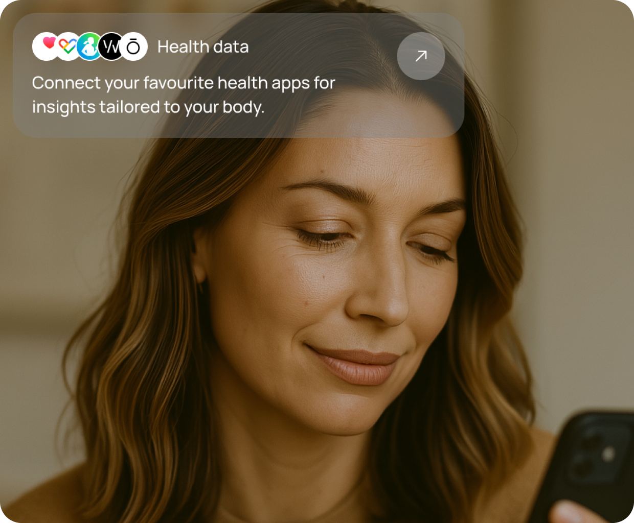 A close-up of a woman smiling softly as she looks at her phone, with a screen overlay prompting connection to health apps like Apple Health, WHOOP, and Google Fit for tailored skin insights.