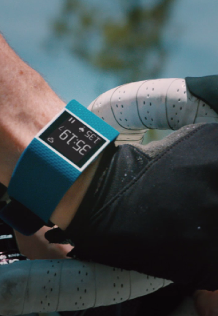 Fitbit close up on a man's wrist who is riding a race bike with skin indexes as overlays.