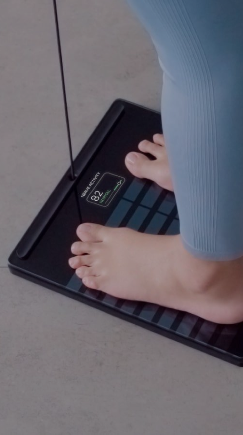 Close-up of a person’s feet on a Withings Body Smart scale in a home setting.