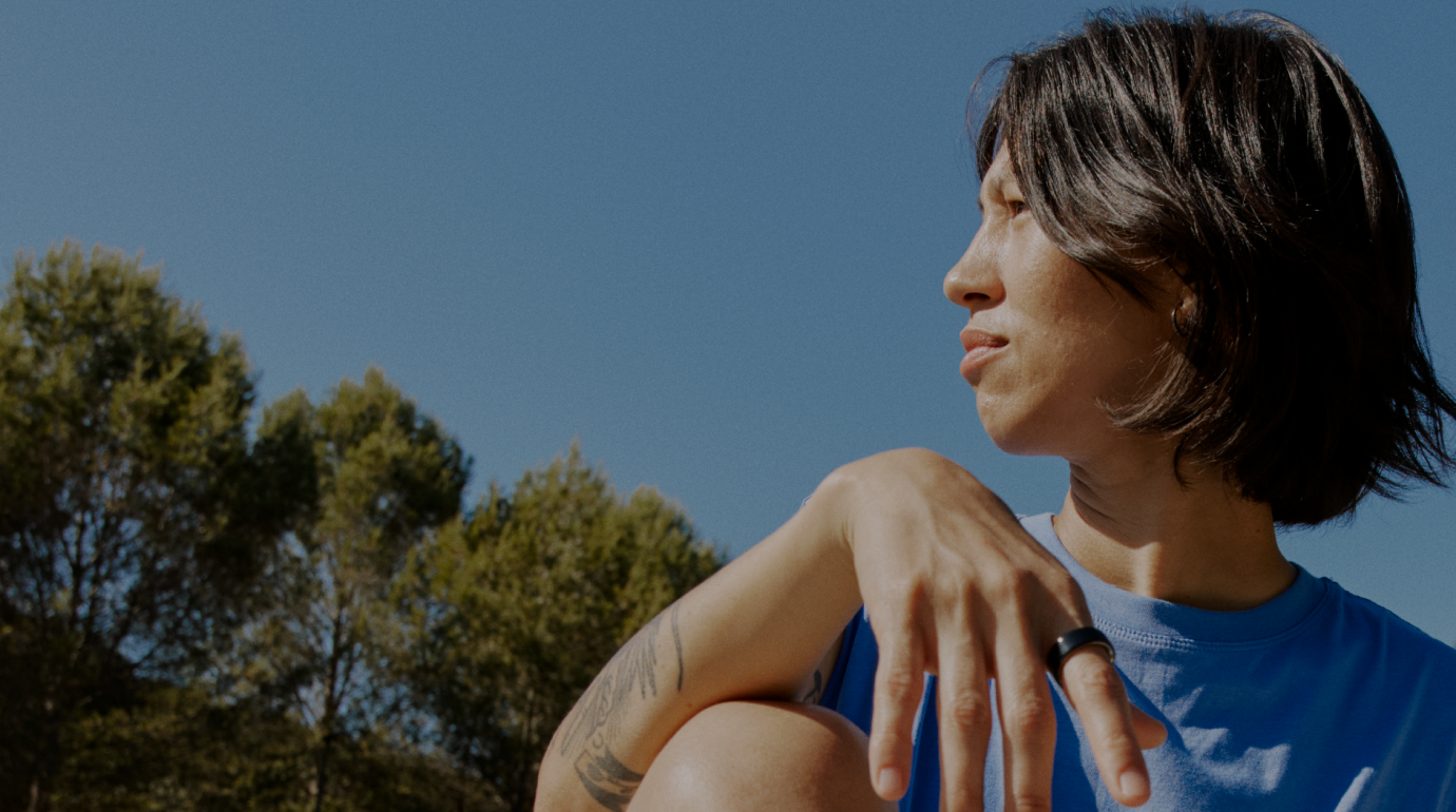 A woman wearing an Oura Ring sits in natural light, reflecting calmly. A Stella overlay shows a skin insight synced from Oura data.