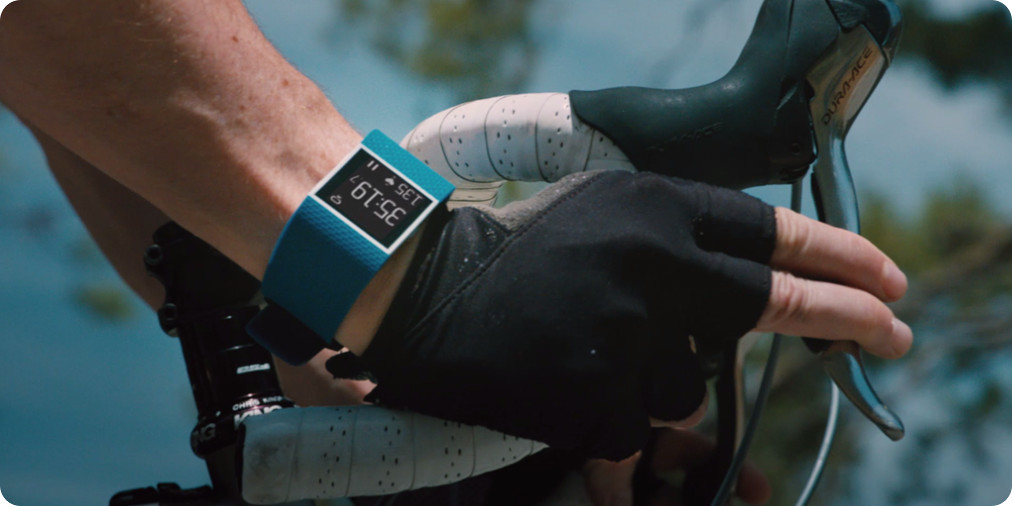 Fitbit close up on a man's wrist who is riding a race bike with skin indexes as overlays.