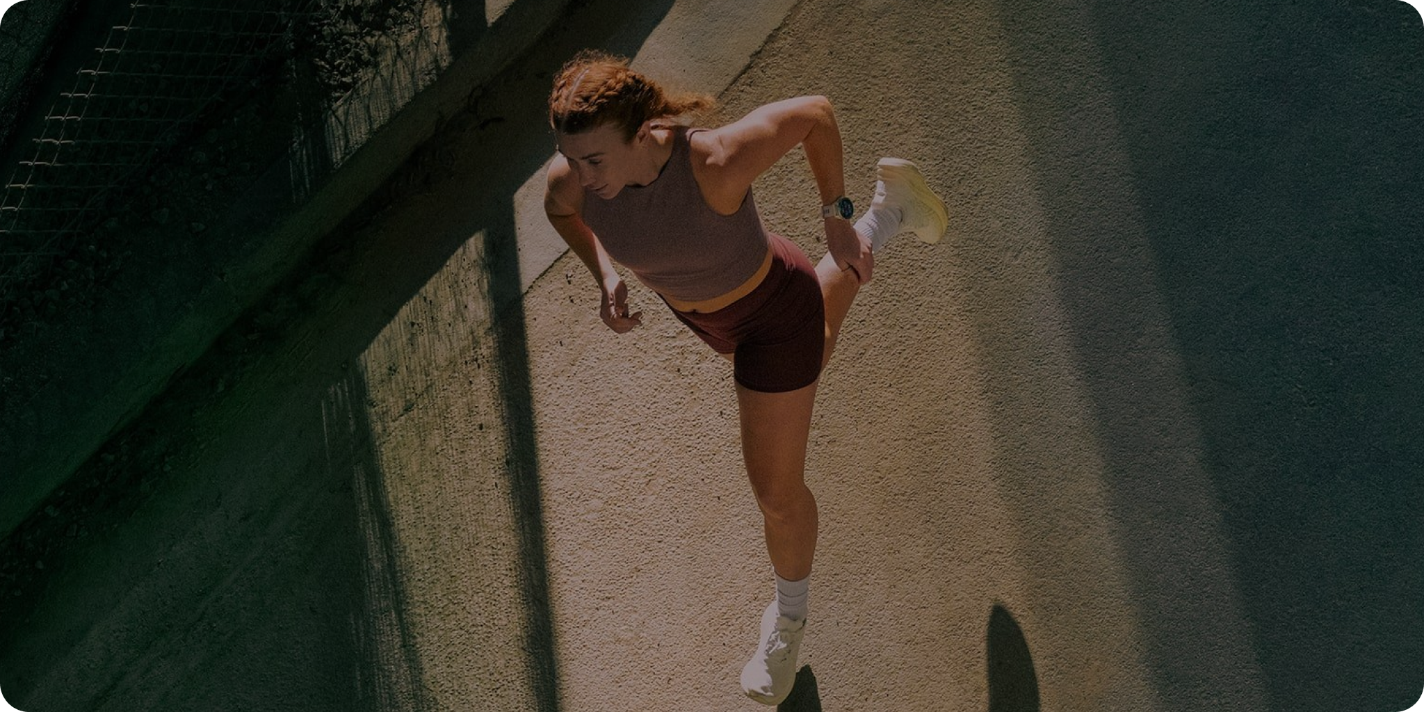 Woman running on a road from an arial view wearing a Garmin watch with Stella overlays.